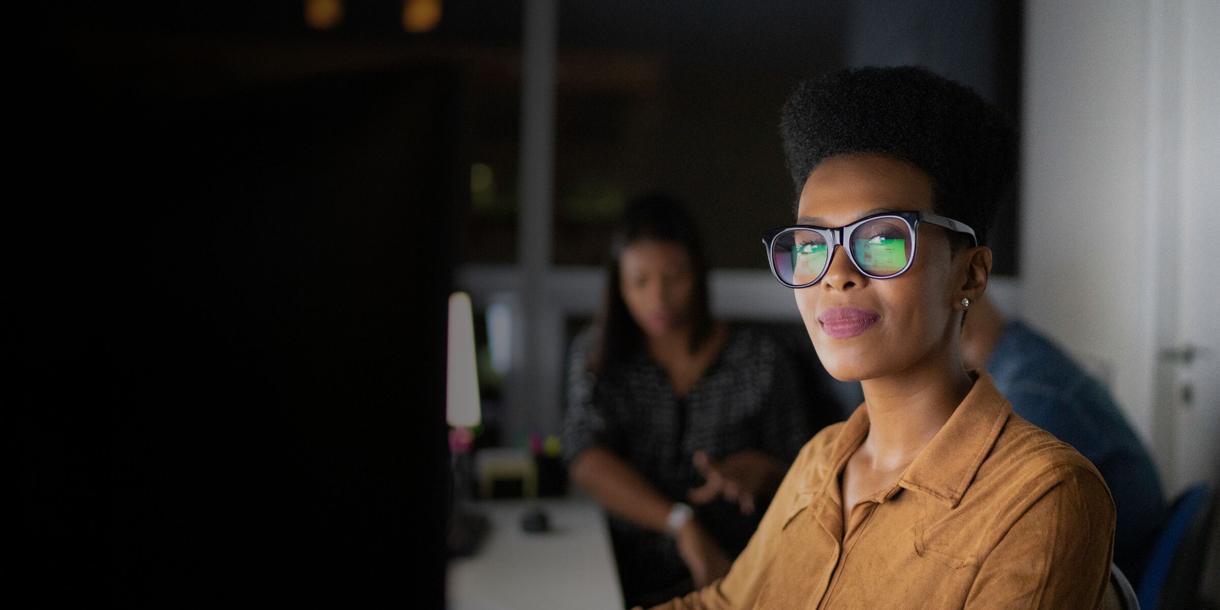 business woman wearing glasses smiling sitting at desk