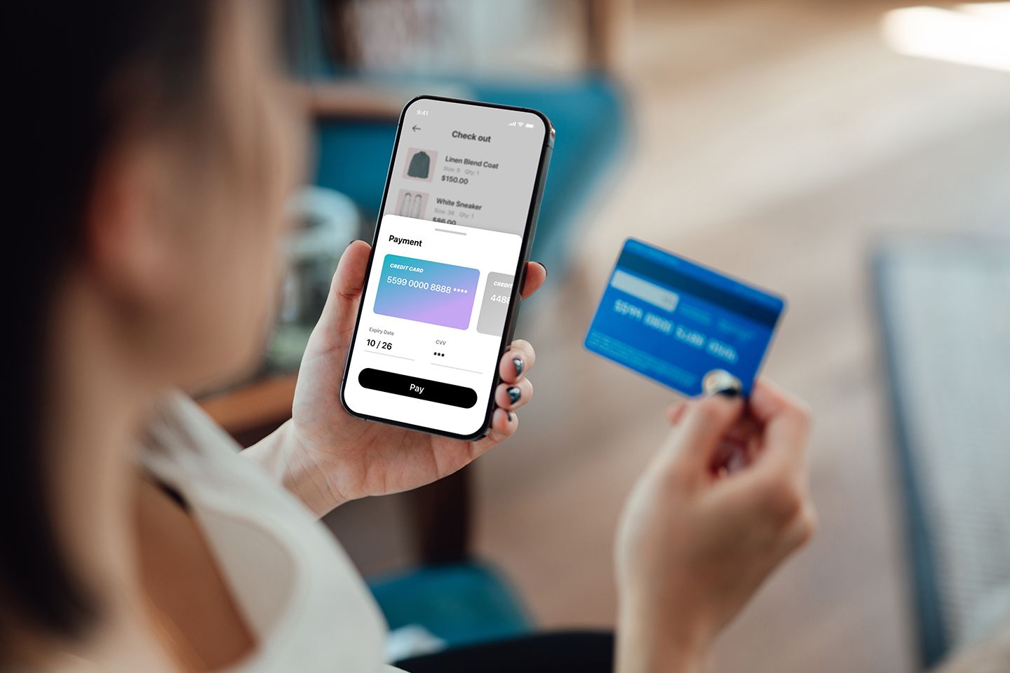 woman holding a credit card next to her smartphone