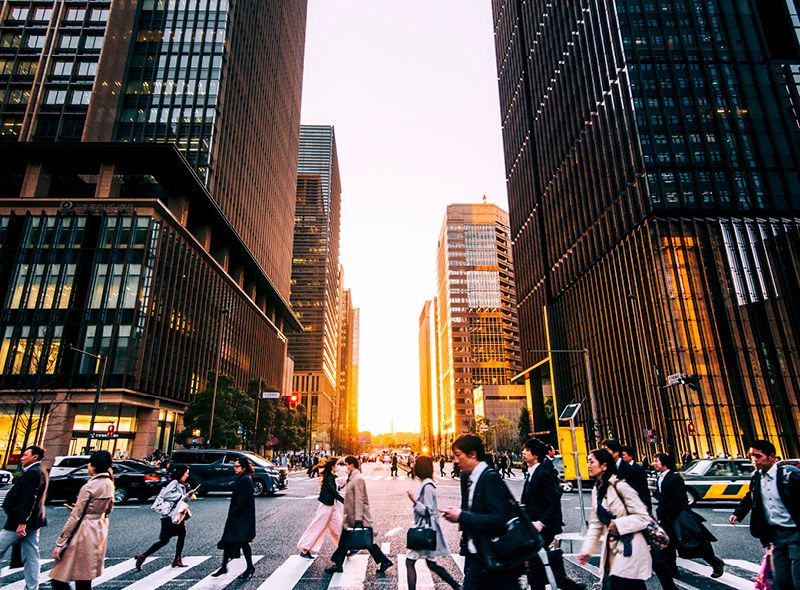 Asian woman standing in front of buildings looking at phone