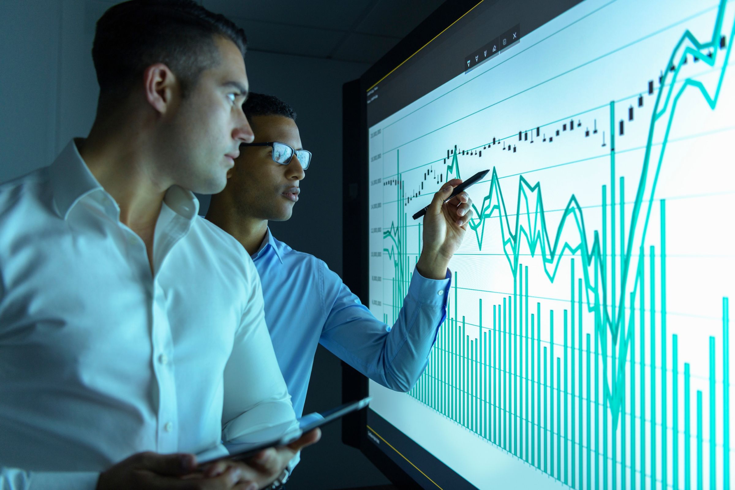 2 businessmen looking at digital screen with chart