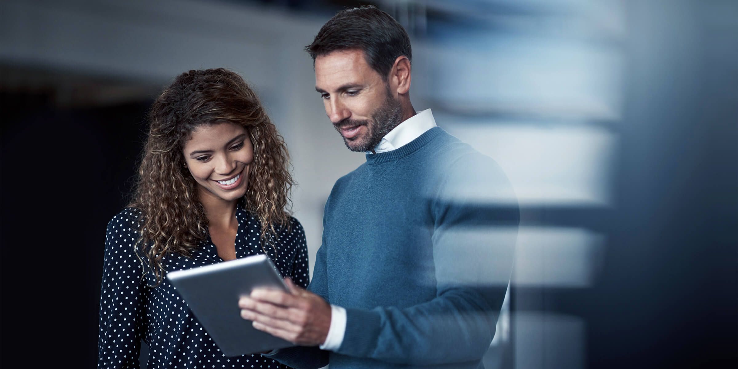 Business man and woman smiling looking at tablet