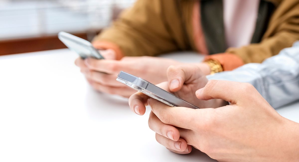 Two sets of hands holding phones