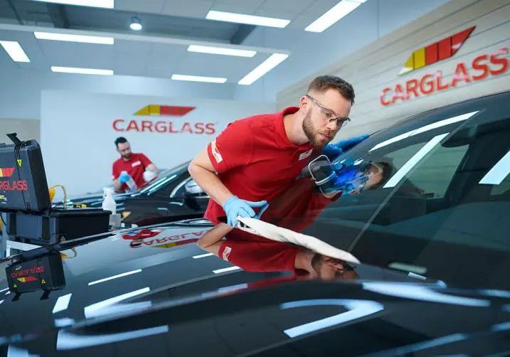 man installing a windshield on a car