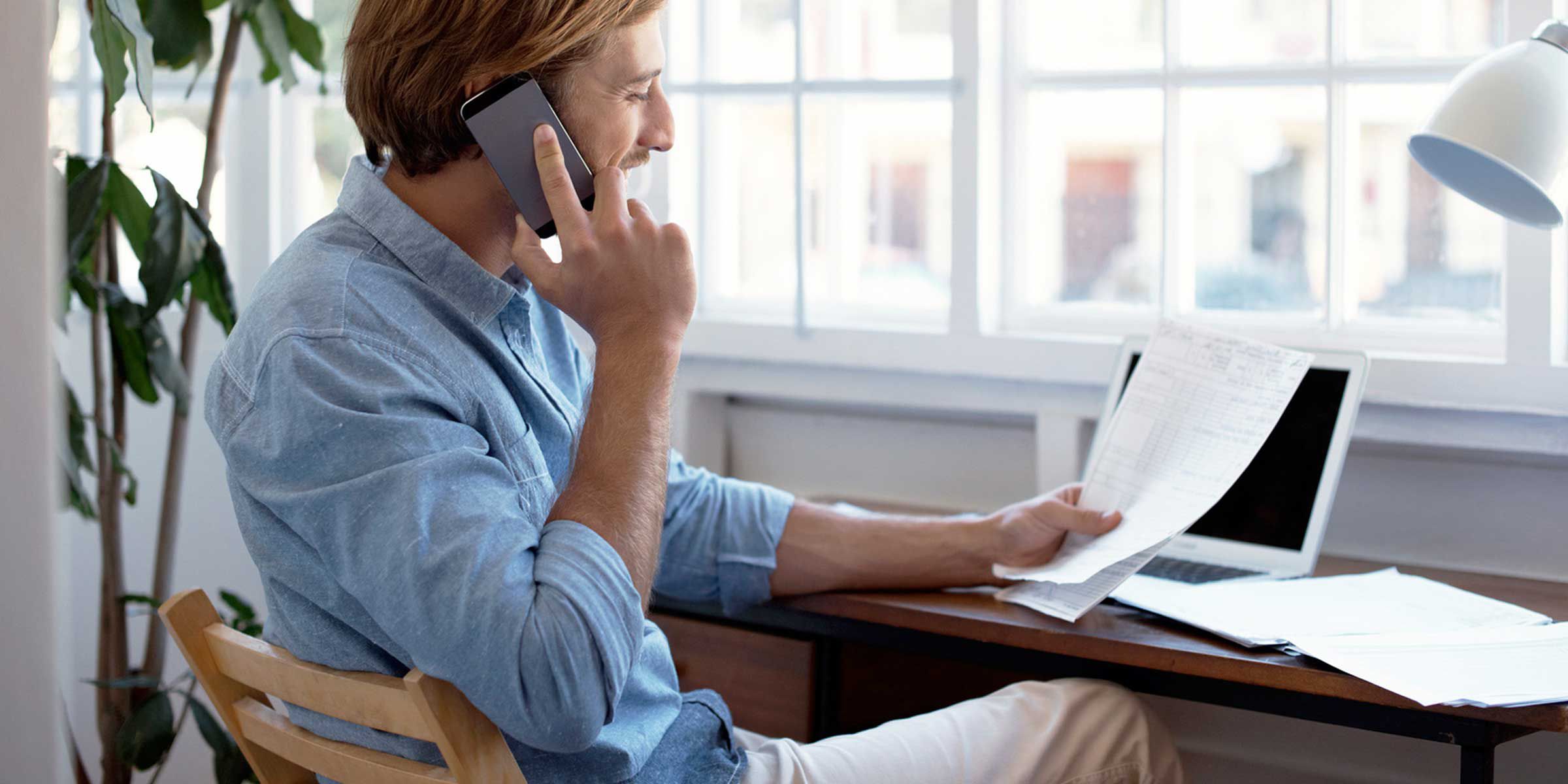 a man on the phone and looking at a paper