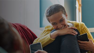 Smiling person sitting indoors holding a phone