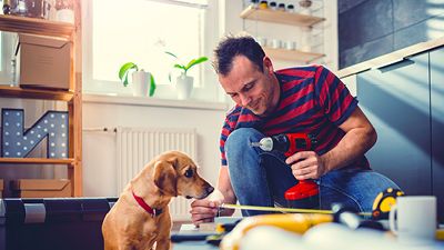 Man drilling hole, dog watching