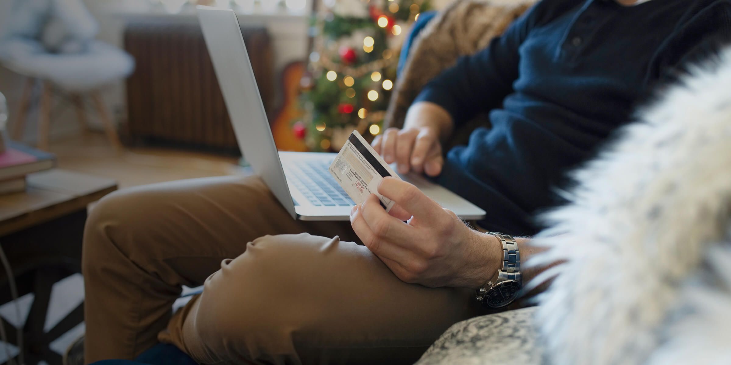 person holding a card while typing on laptop