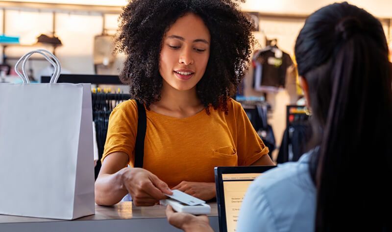 Woman paying by card at a clothing store. Happy Latin American woman paying by card at a clothing store - small business concepts