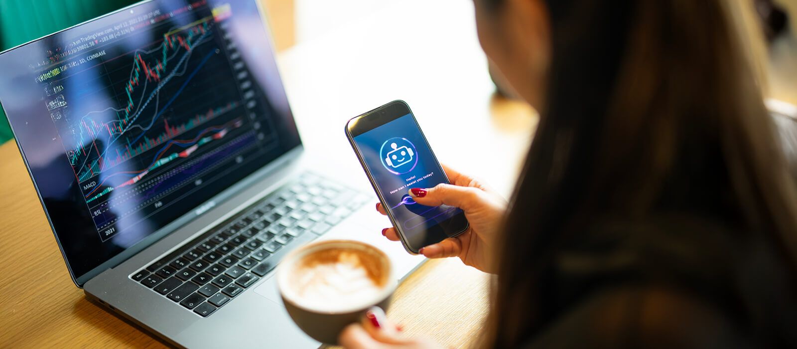 woman working at laptop looking at phone and holding coffee