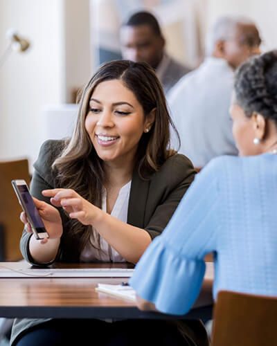 a businesswoman at a bank is teaching a lady how to open an account