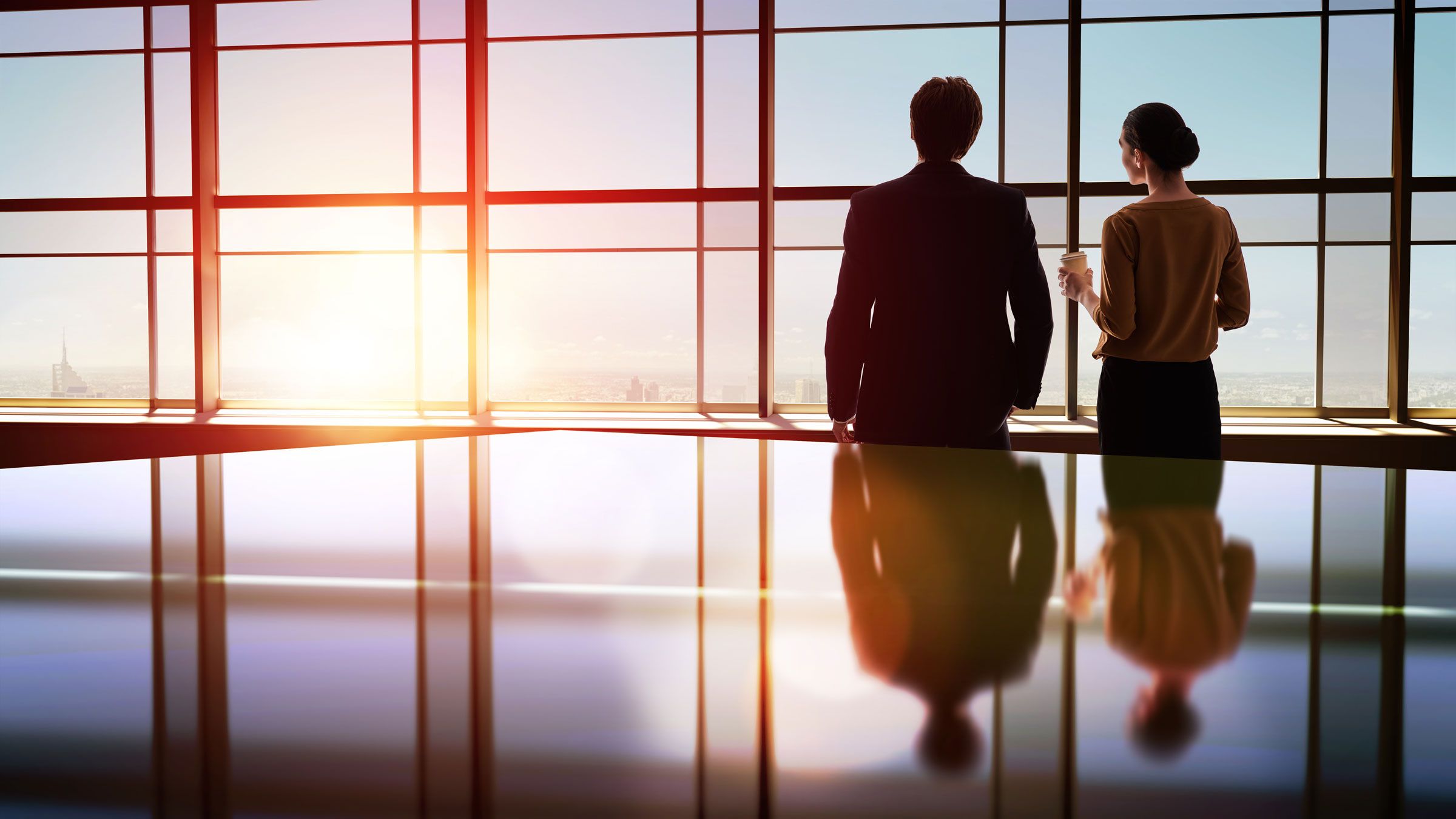 two people looking out an office building window