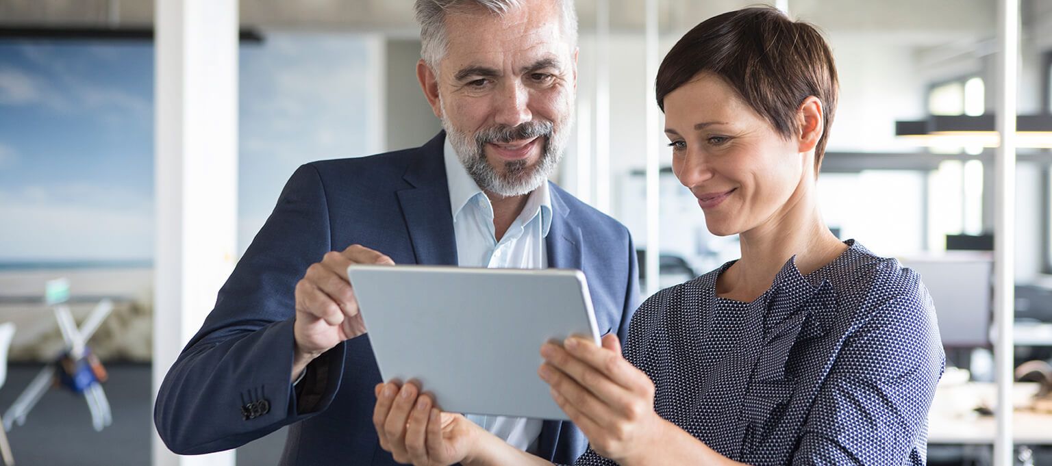 a man and woman looking at a tablet