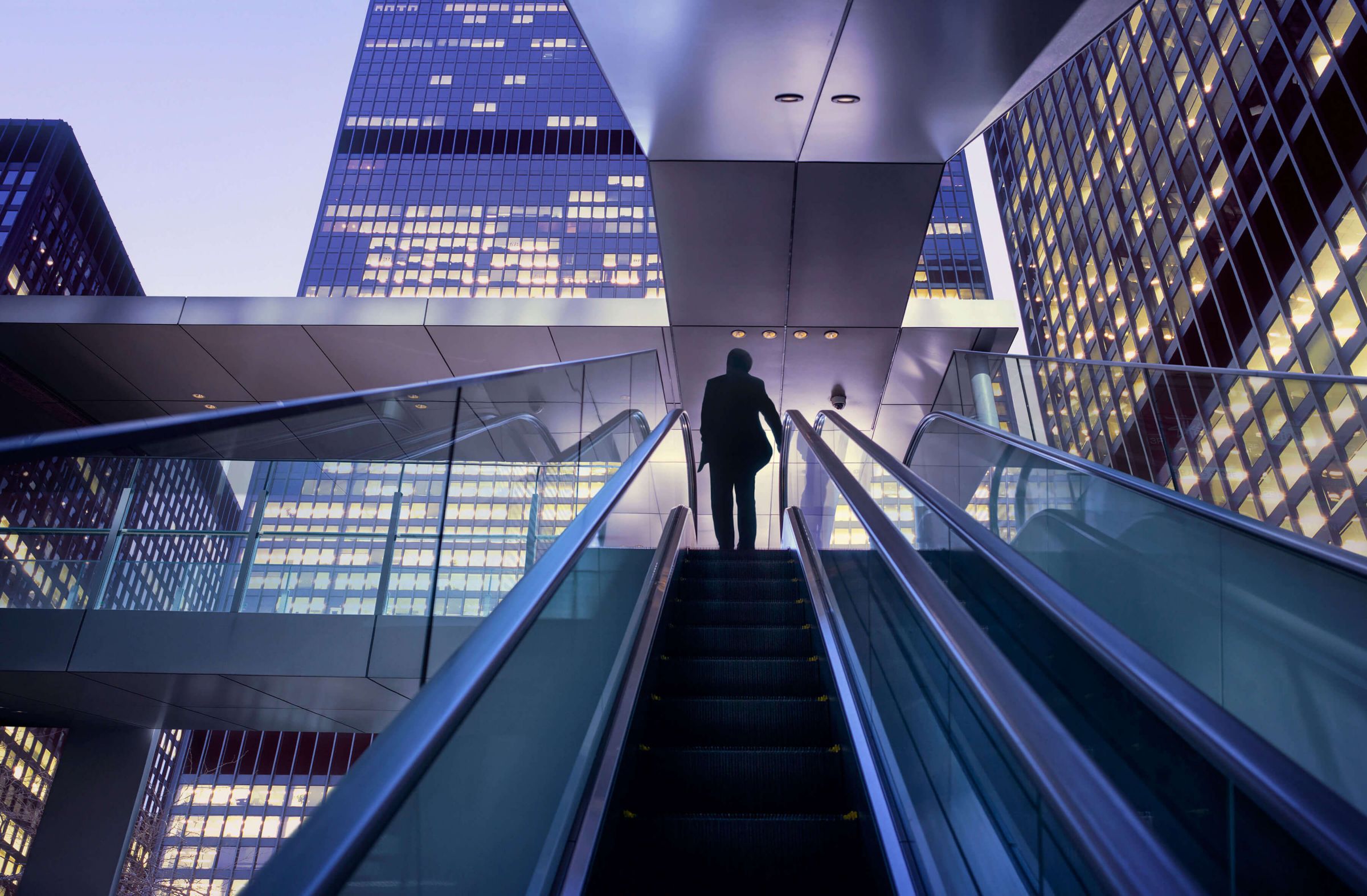 person riding up outdoor escalator