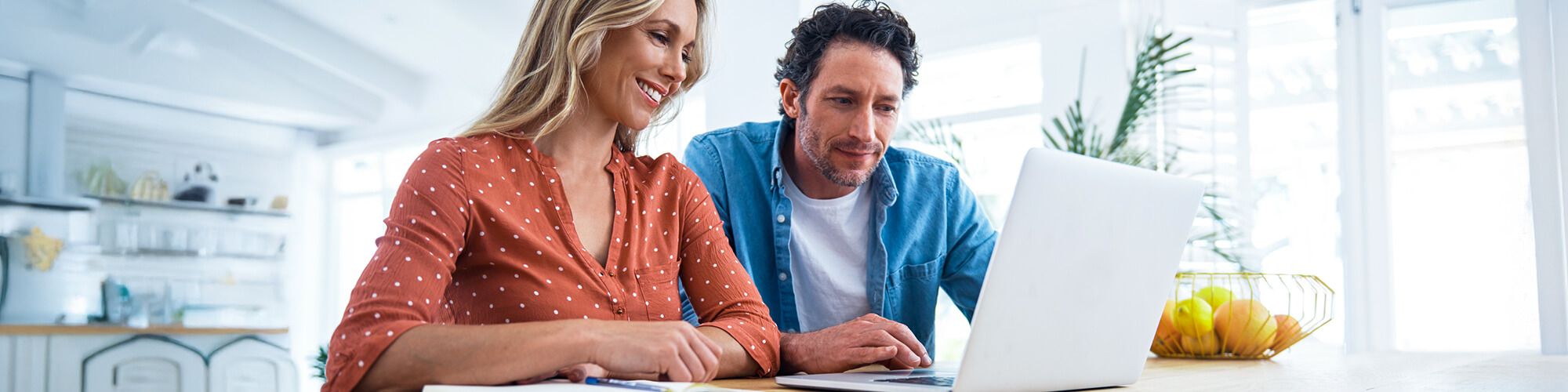Couple sitting at table looking at laptop