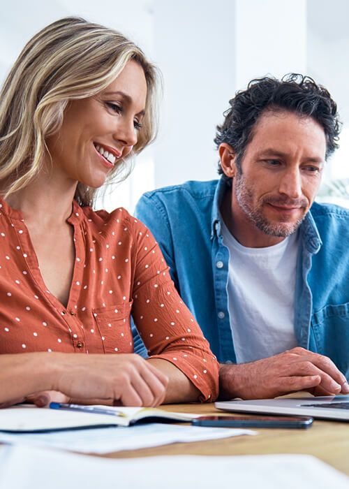 Couple sitting at table looking at laptop