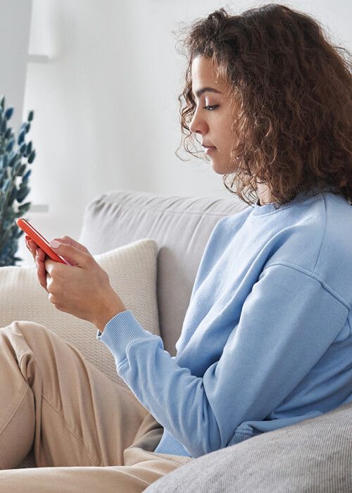 Woman sitting on sofa looking at phone