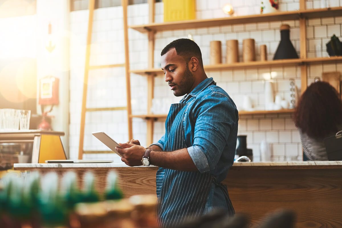 small businessman wearing apron holding a tablet