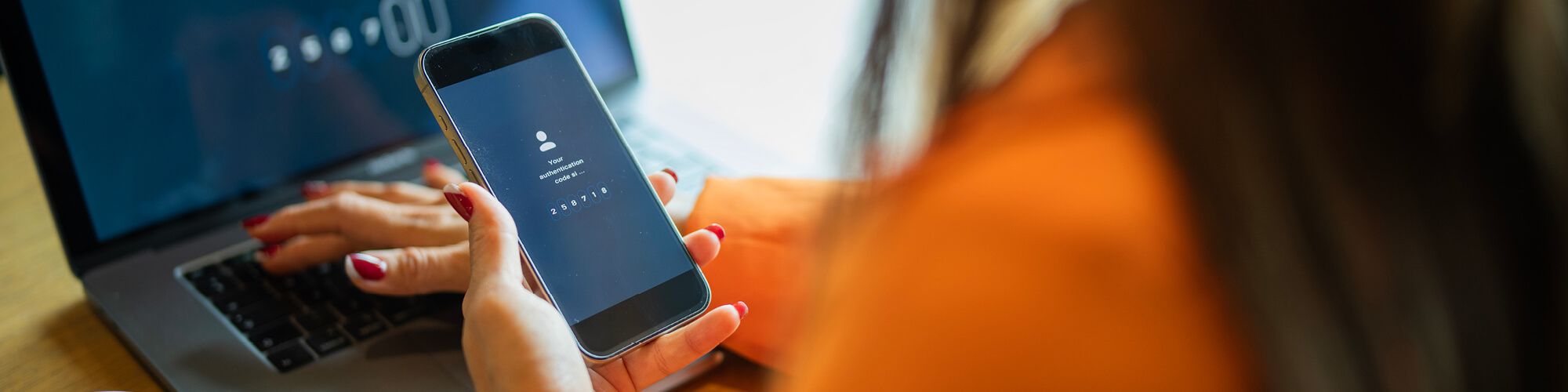female at laptop using mobile phone