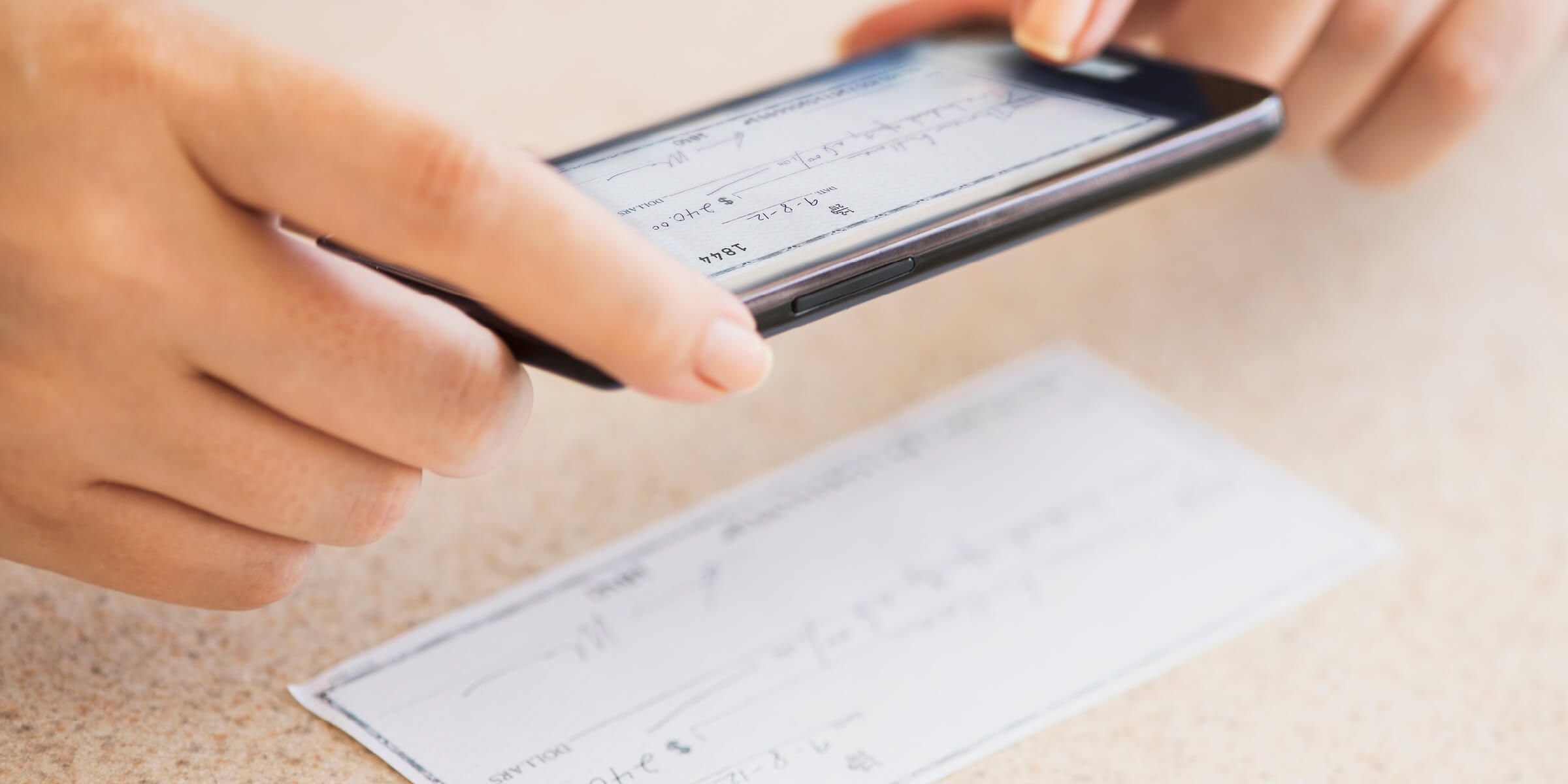 person taking picture of check with phone