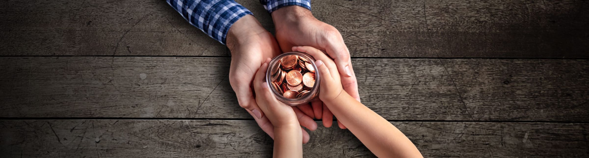 parent and child hands holding pennies in a jar