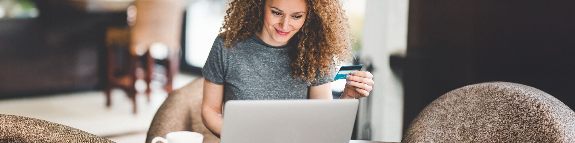 women working on laptop holding credit card