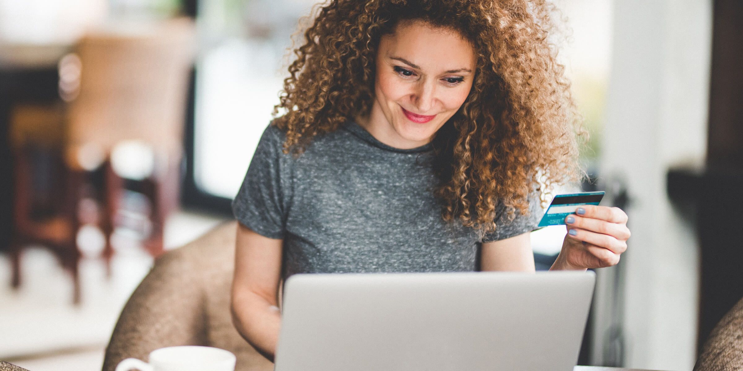 woman smiling holding credit card and typing on laptop