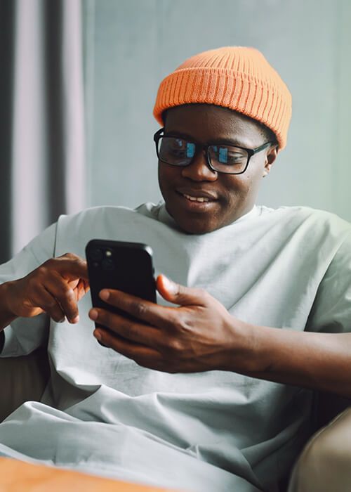 Online shopping. A man makes purchases on the Internet using a smartphone at home in the living room. Comfortable shopping at home. A man makes purchases on the Internet using a smartphone at home in the living room.