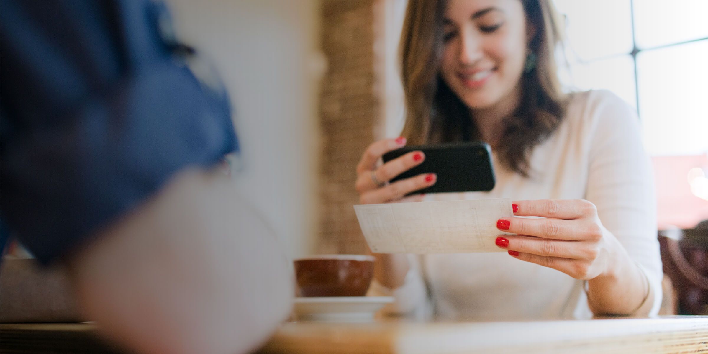  a woman is holding a phone in one hand and a check in the other