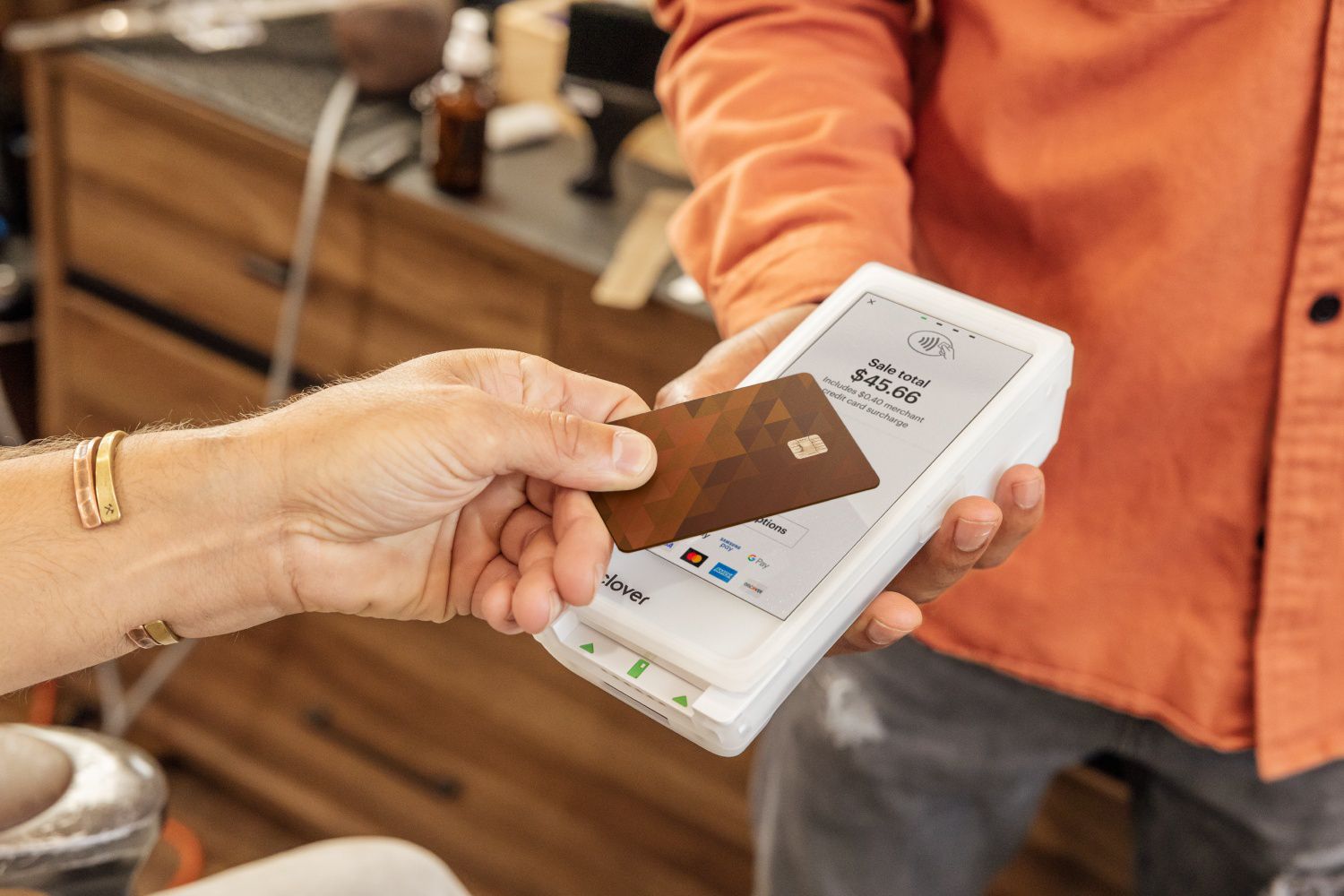 customer is swiping a credit card on a portable payment terminal held by a cashier