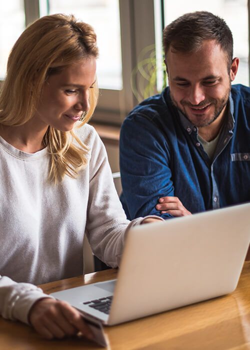 a man and woman looking at a laptop
