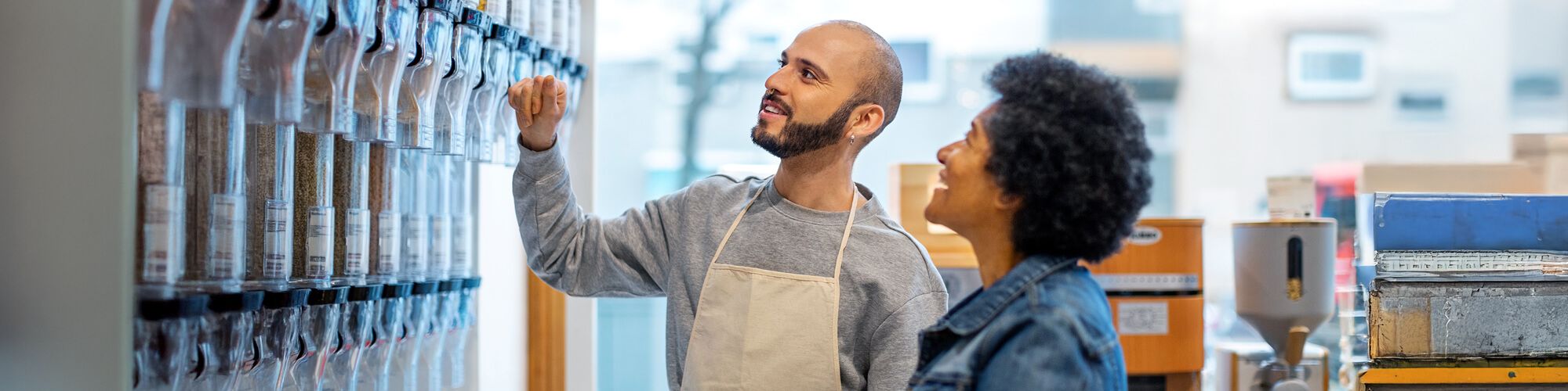 small businessman wearing apron helping a female customer