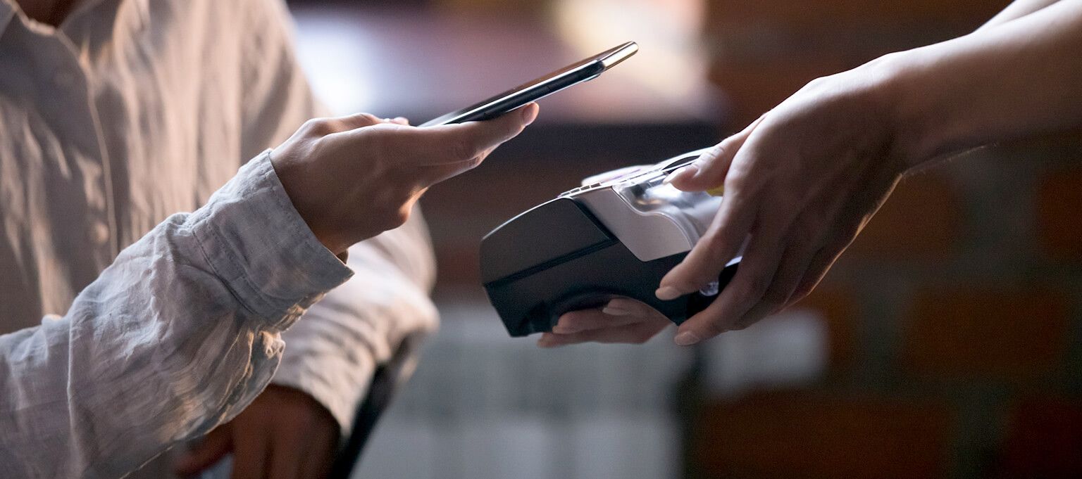 a person hand shown paying with a mobile phone