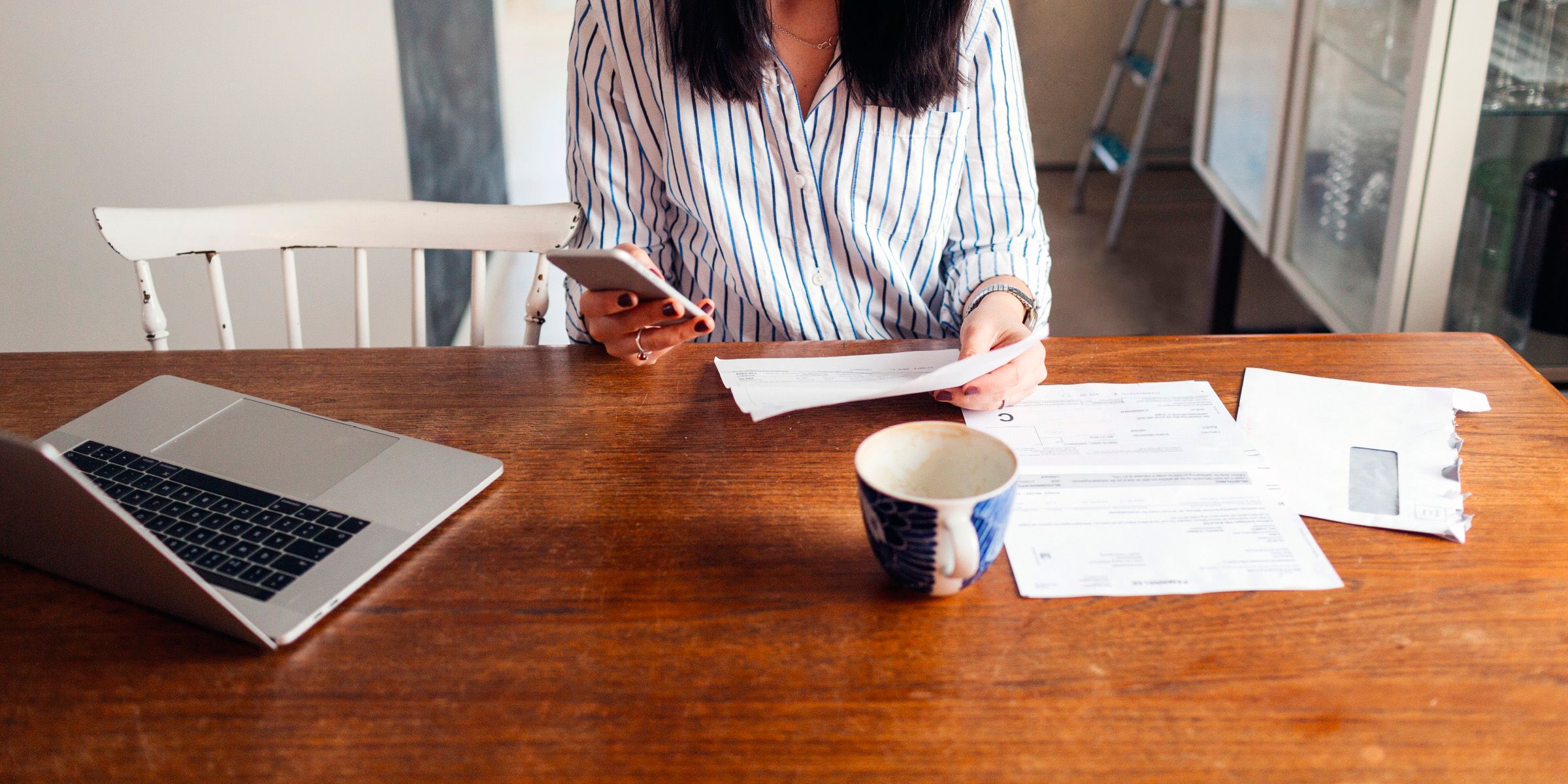 woman sitting at a table paying a bill with her smartphone