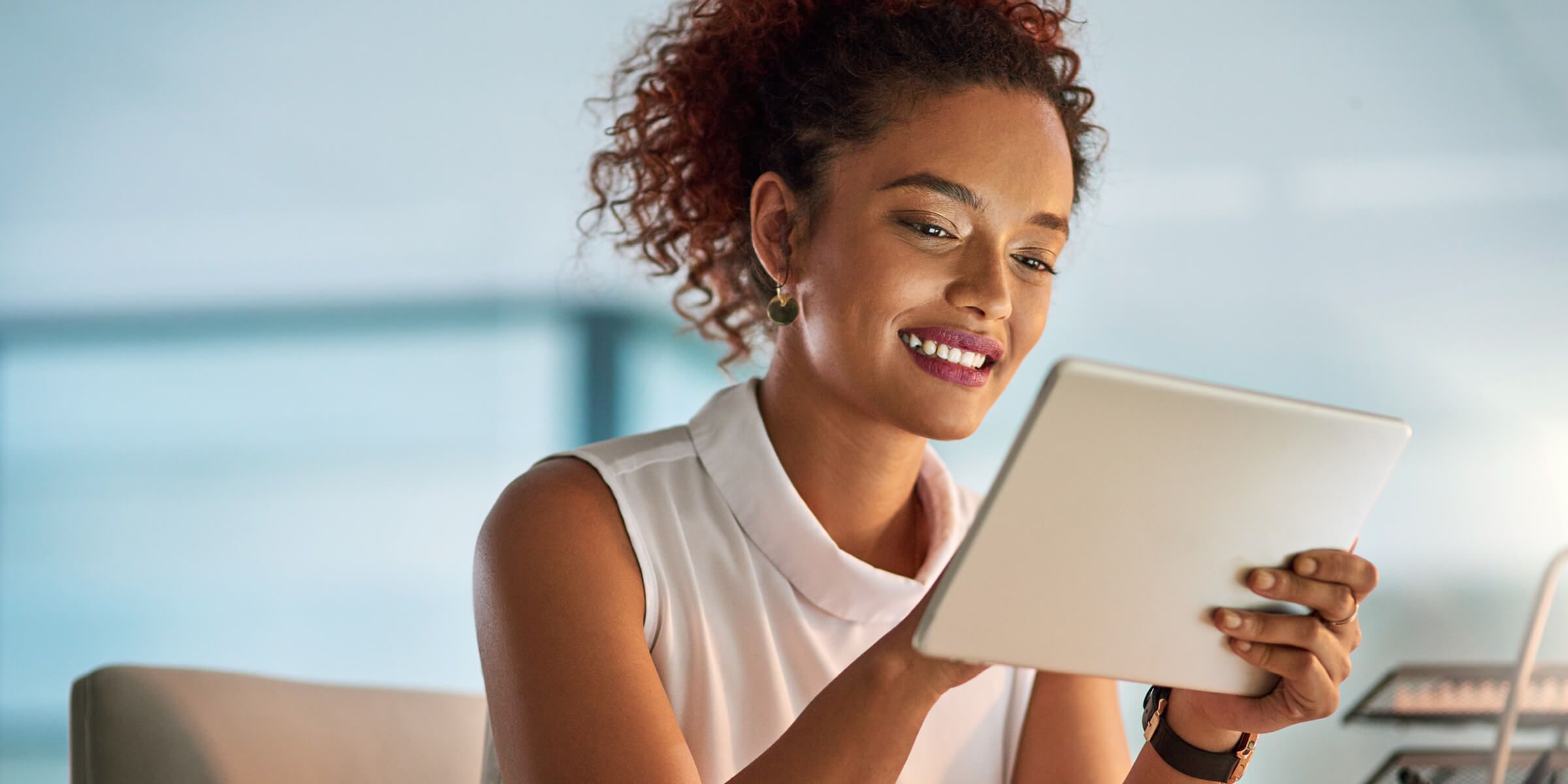 a woman smiling looking at a tablet