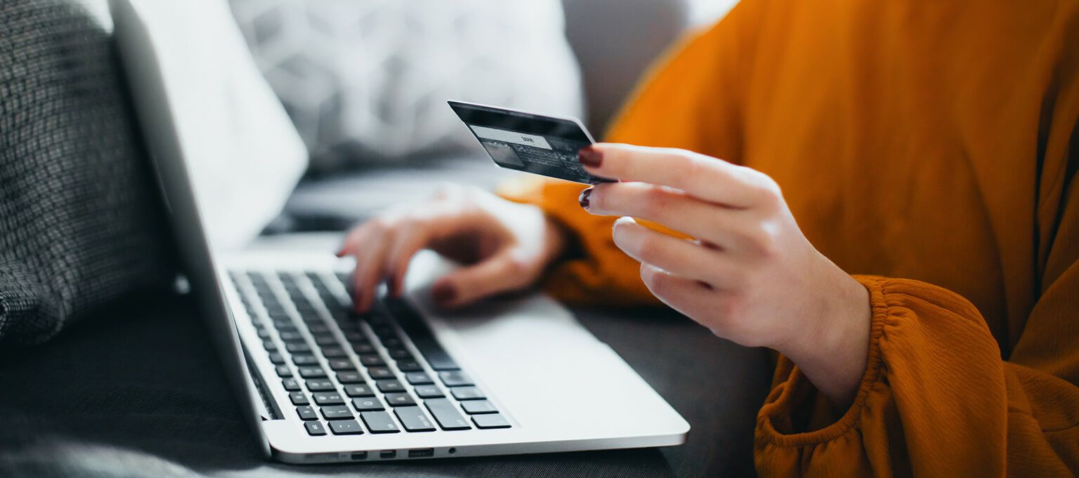 a person holding a credit card and typing on a laptop