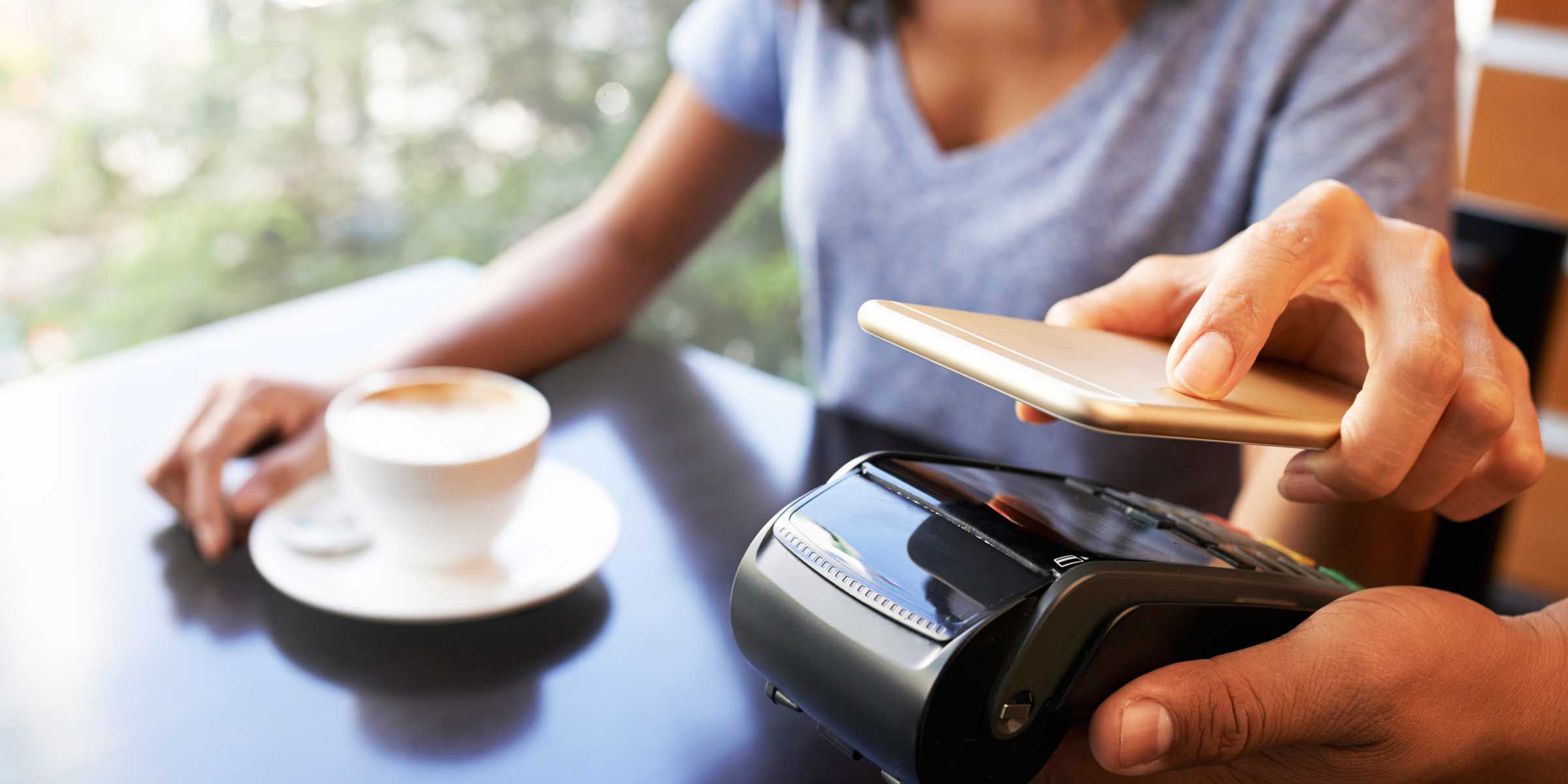 Women at coffee shop paying with phone at table