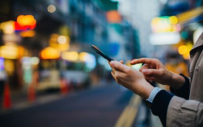 person standing on street typing on phone