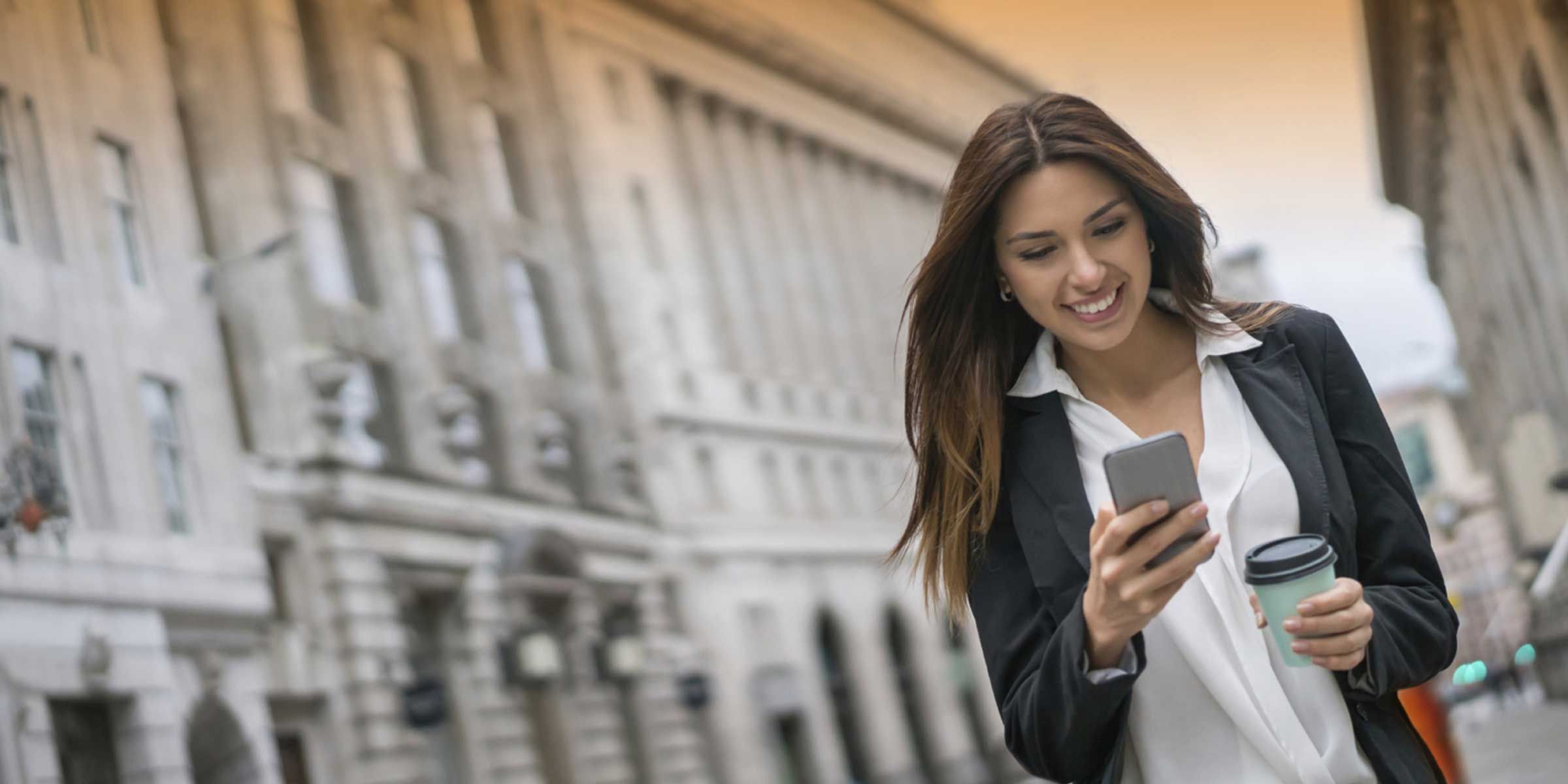 a woman smiling while looking at her phone