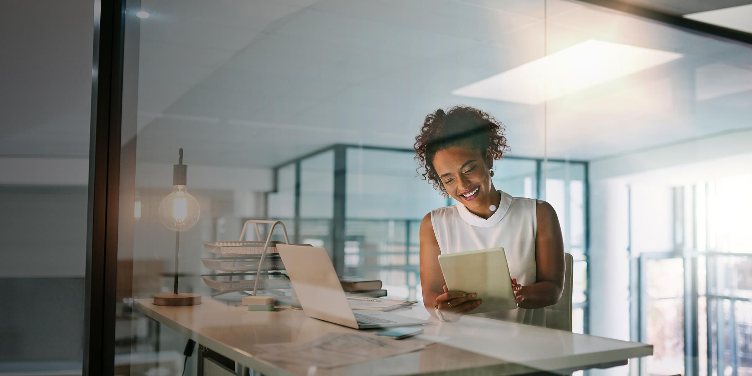 business woman sitting at desk in office looking at tablet